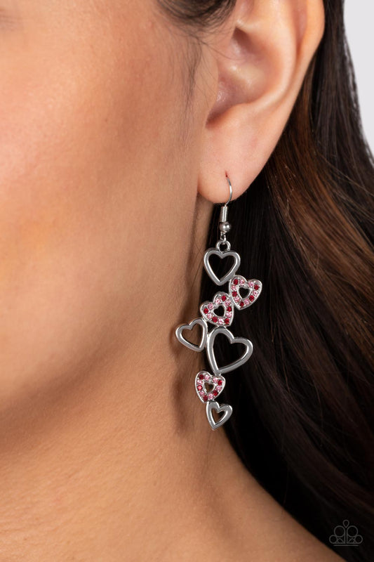 Sweetheart Serenade - Red and Pink Earrings - Paparazzi Accessories - Bejeweled Accessories By Kristie - A collection of airy, heart-shaped silhouettes fall from the ear in a bubbly cascade. In a haphazard pattern, the sleek and simple silver frames alternate with those lined with sparkling siam and light rose rhinestones, culminating in a flirtatious lure. Earring attaches to a standard fishhook fitting. Sold as one pair of earrings.