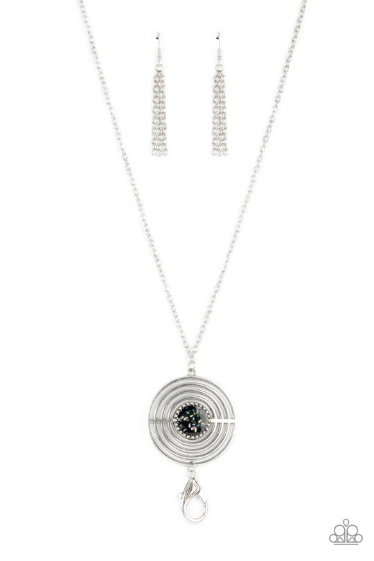 Targeted Tranquility - Black and Silver Lanyard Necklace - Paparazzi Accessories - Flecked in iridescent shell-like accents, a studded black frame adorns the center of an oversized silver pendant rippling with concentric circles at the bottom of an extended silver chain for a dizzying pop of color. A lobster clasp hangs from the bottom of the design to allow a name badge or other item to be attached. Features an adjustable clasp closure.