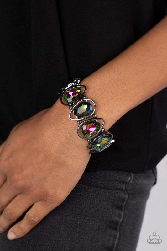 The Sparkle Society - Multi Color - Oil Spill Bracelet - Paparazzi Accessories - Bejeweled Accessories By Kristie - Oversized teardrop gems, coated in a shimmery oil spill finish are seemingly suspended inside gunmetal teardrop frames. The airy borders allow the faceted edges of the teardrop beads to take center stage, as the frames, separated by tiny gunmetal beads, wrap around the wrist on stretchy bands.