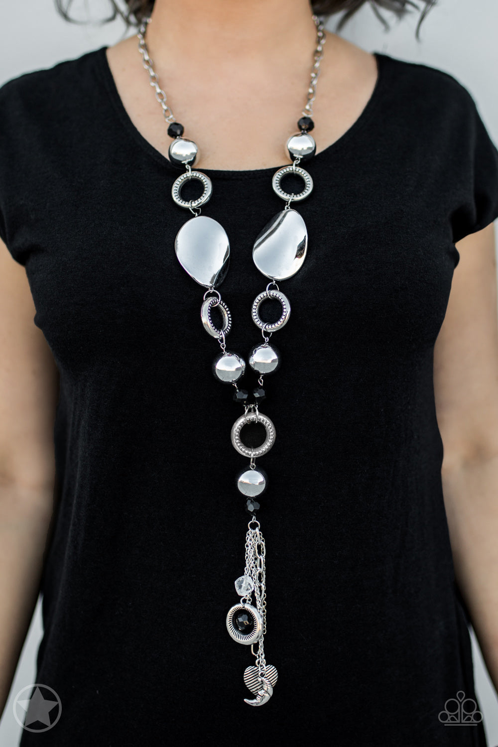 Total Eclipse Of the Heart - Silver and Black Necklace - Paparazzi Accessories - Long chain of black crystalized beads, curved plates of silver with a pearly finish, and chunky silver rings lead down to a tassel of chains and charms, including a crescent moon and a heart. 