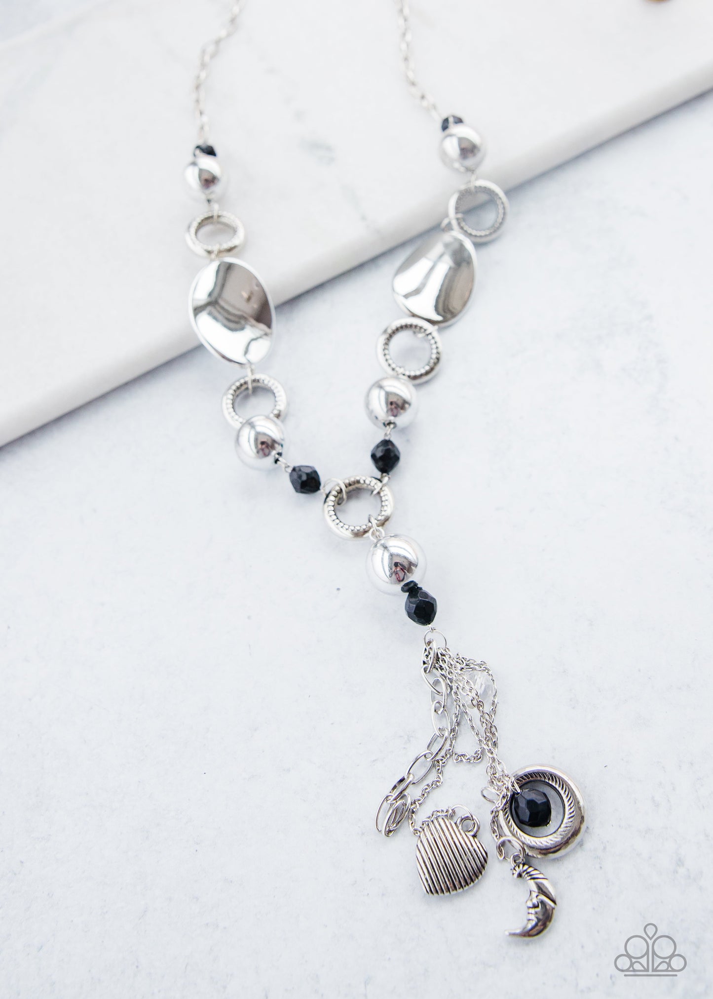 Total Eclipse Of the Heart - Silver and Black Necklace - Paparazzi Accessories -  Bejeweled By Kristie - Long chain of black crystalized beads, curved plates of silver with a pearly finish, and chunky silver rings lead down to a tassel of chains and charms, including a crescent moon and a heart. 