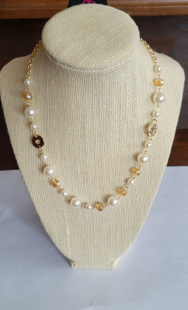 Traditional Transcendence - Gold Pearl Necklace - Paparazzi Accessories - A timeless collection of white pearls, golden crystal-like beads, and hammered gold discs delicately connects below the collar, resulting in a refined display. Features an adjustable clasp closure. Sold as one individual necklace.