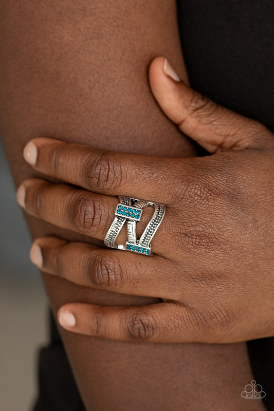 Urban Upscale - Blue and Silver Ring - Paparazzi Accessories - 
Etched and dotted in mismatched textures, three shimmery silver bars wave across the finger. Encrusted in dainty blue rhinestones, glittery frames connect the swooping bands for a refined look. Features a stretchy band for a flexible fit. Sold as one individual ring.
