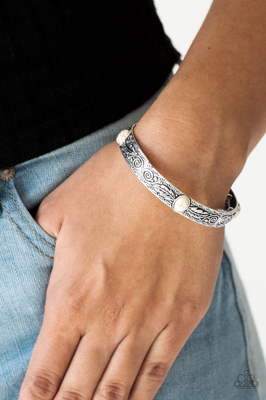Wild West Story - White Stone and Silver Bracelet - Paparazzi Accessories - Silver and feather like detail, antiqued silver frames are threaded along stretchy bands around the wrist. Refreshing white stones adorn the centers of the Southwestern frame bracelet.