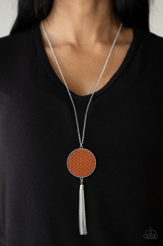 Wondrously Woven - Brown Leather - Silver Necklace - Paparazzi Accessories - Featuring a faux woven finish, a shiny piece of Adobe leather is pressed into a studded circular frame at the bottom of a lengthened silver chain. Capped in a frame, a silver chain tassel streams out from the colorful pendant for a playful finish. Features an adjustable clasp closure.